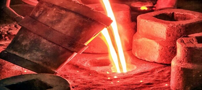 Hot crucible pouring molten metal into refractory material lined molds